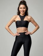 Woman wearing a black sports bra and leggings on a gray background