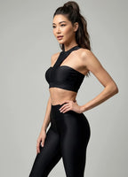 Woman wearing luxury black sports bra and leggings posing on a gray background