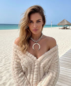 Woman on a beach wearing a silver statement necklace, bohemian chic style. 