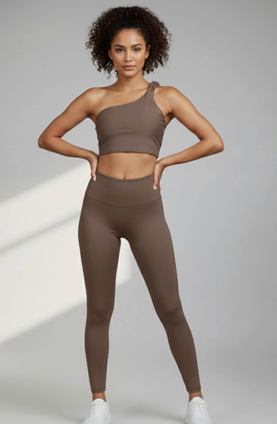Woman wearing a brown sports bra and leggings on a gray background