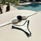 Close-up of removable flower detail on off-white bandeau bikini top.