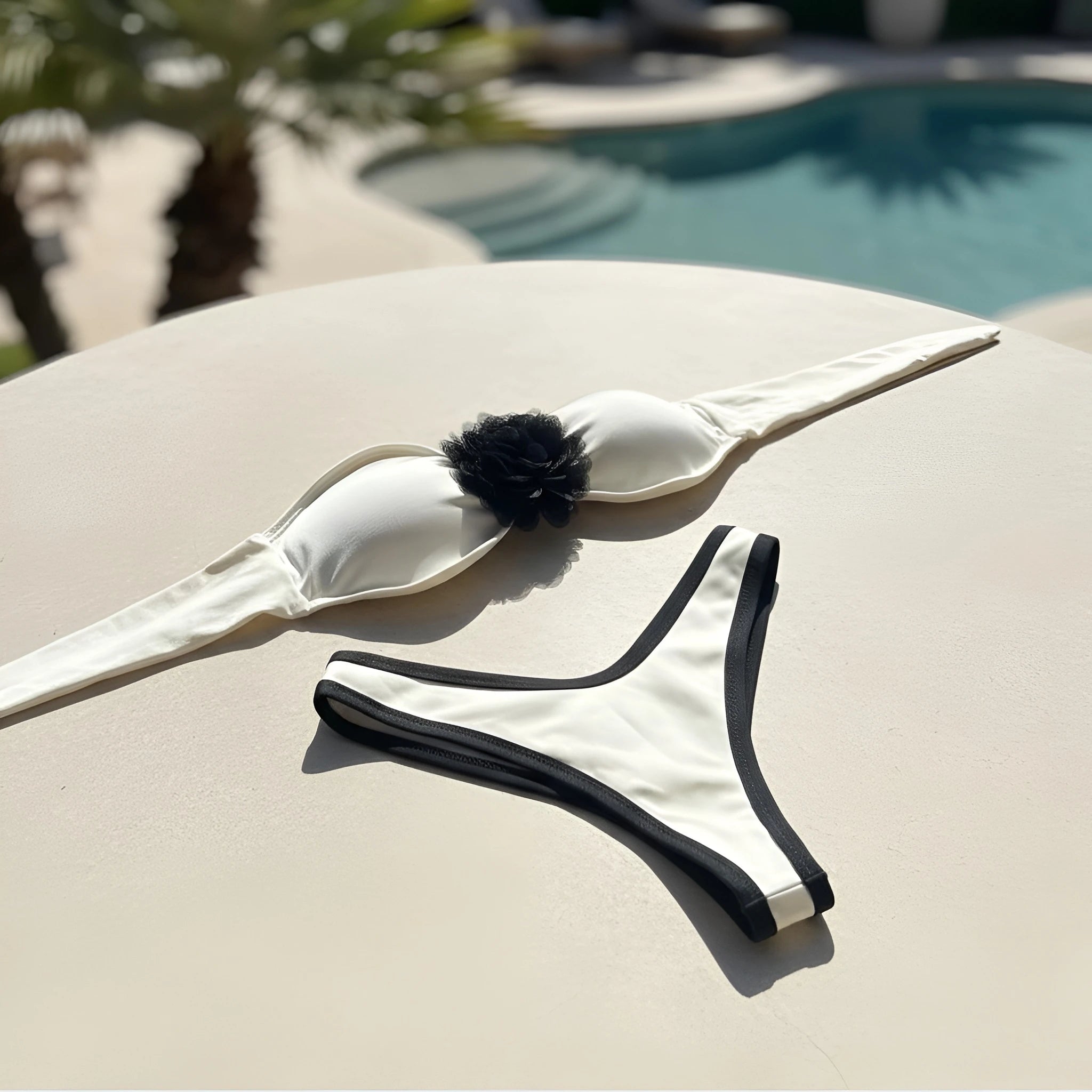 Close-up of removable flower detail on off-white bandeau bikini top.